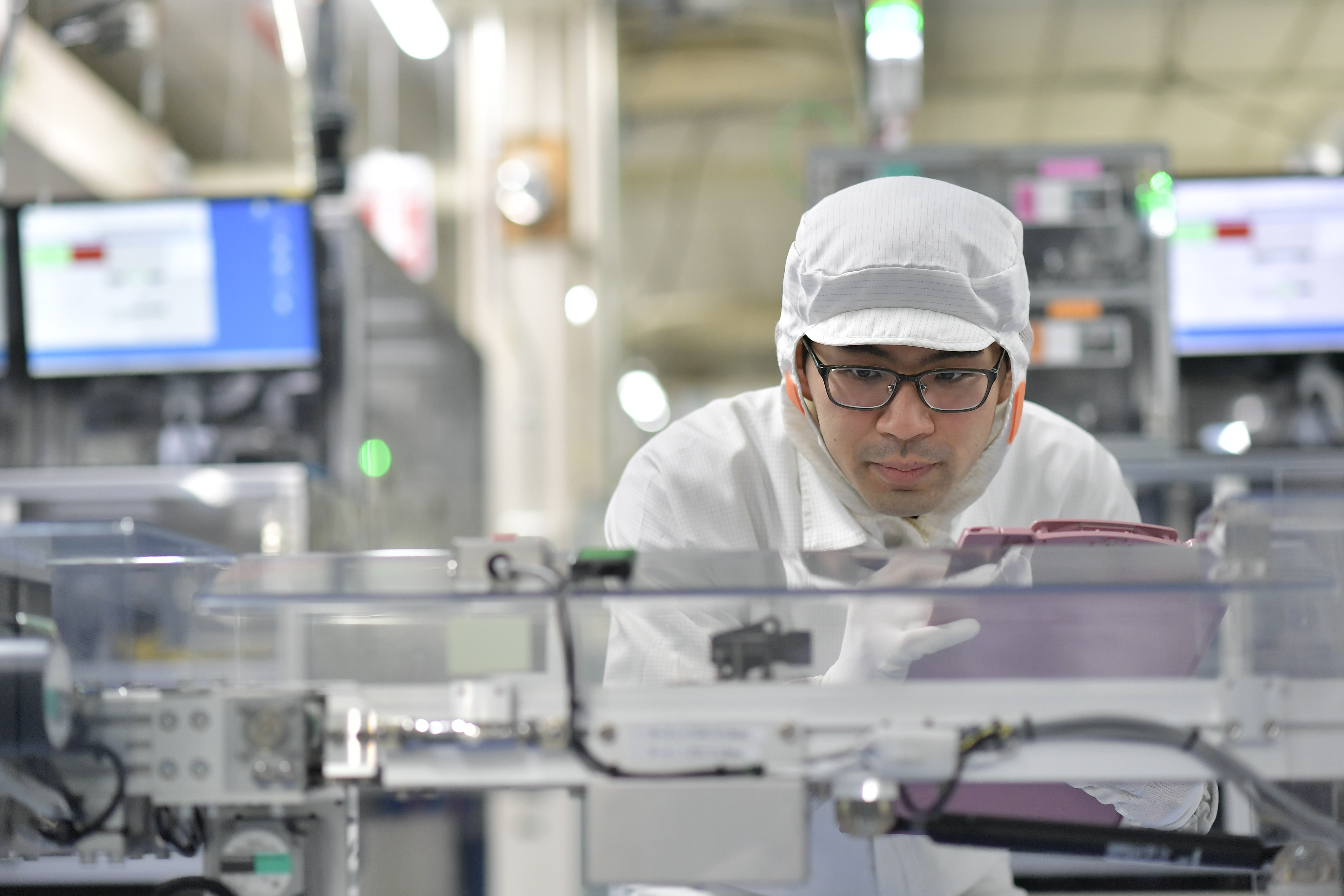 a person in a white robe and glasses working in a factory