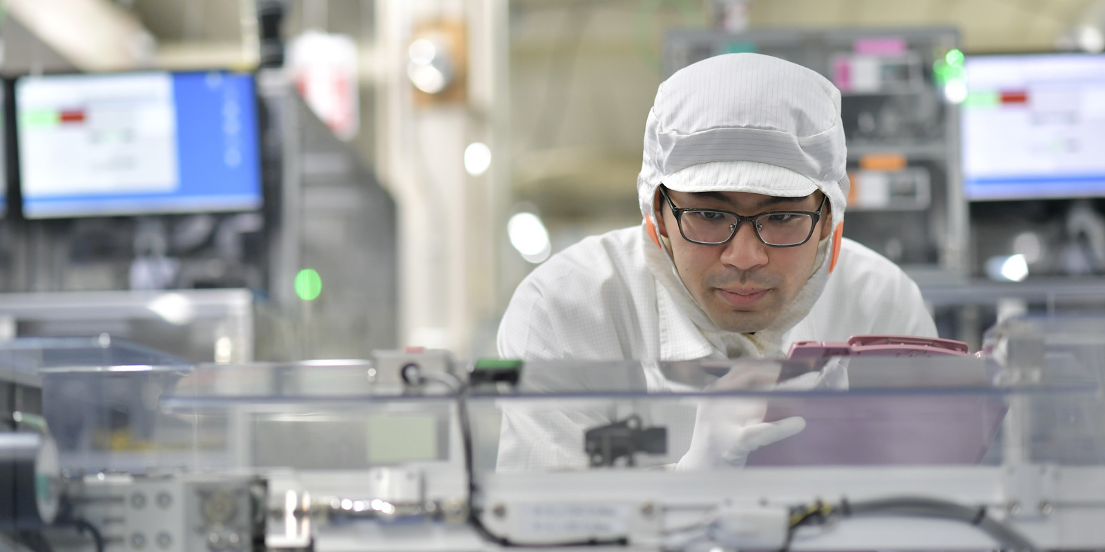 a person in a white robe and glasses working in a factory