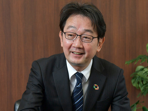 スーツとネクタイを着た人が機械のある机に座っている