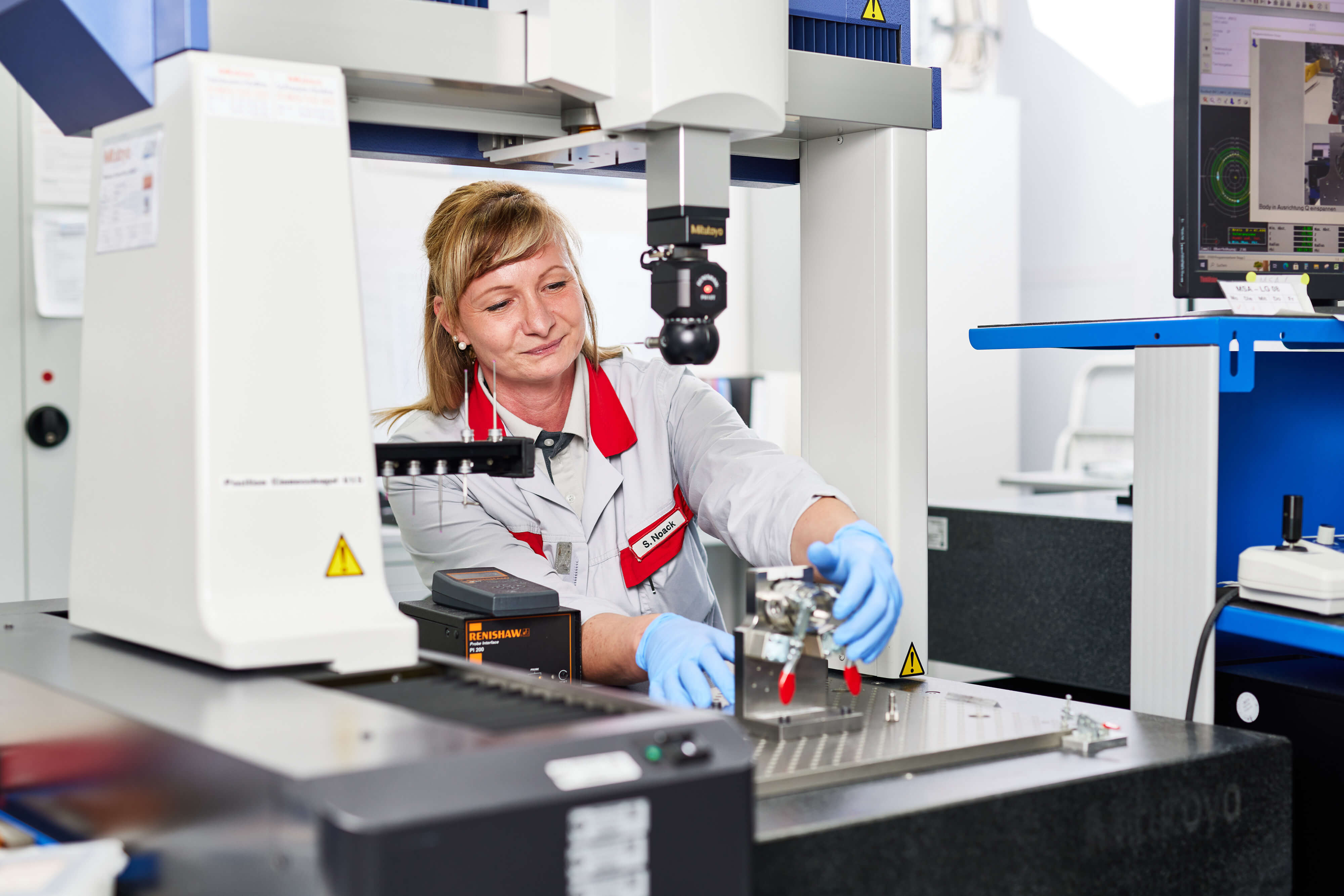 a person in a lab coat and gloves working on a machine