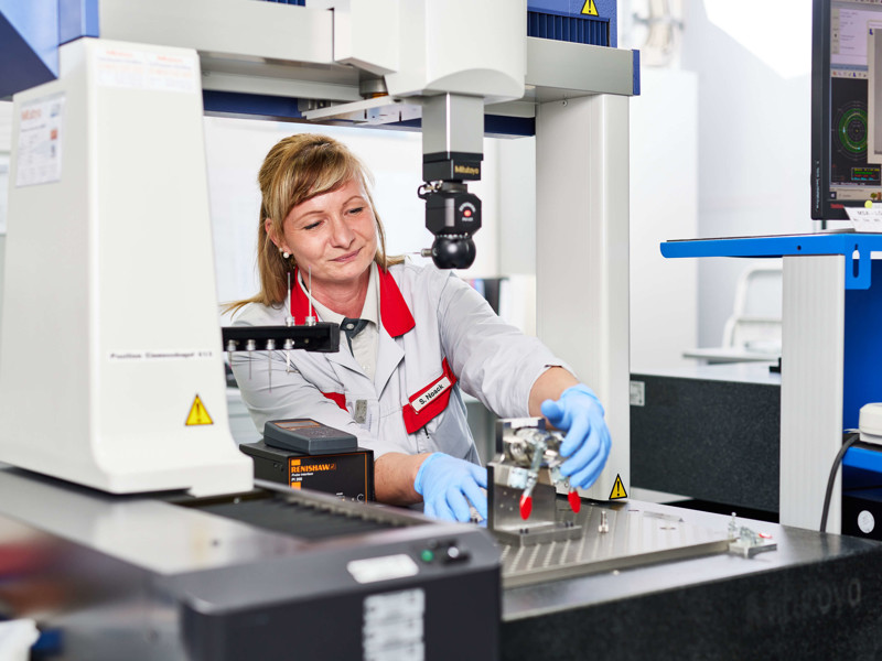 a person in a lab coat and gloves working on a machine