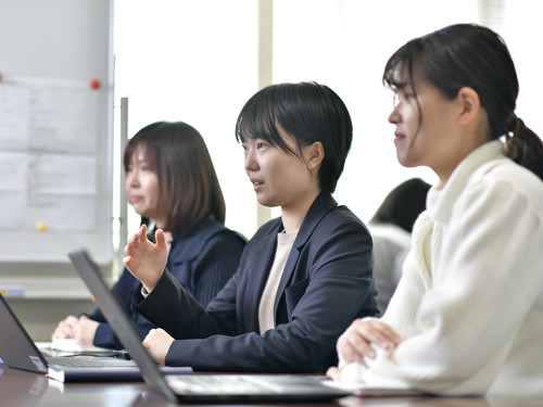 a group of women sitting at a table with laptops
