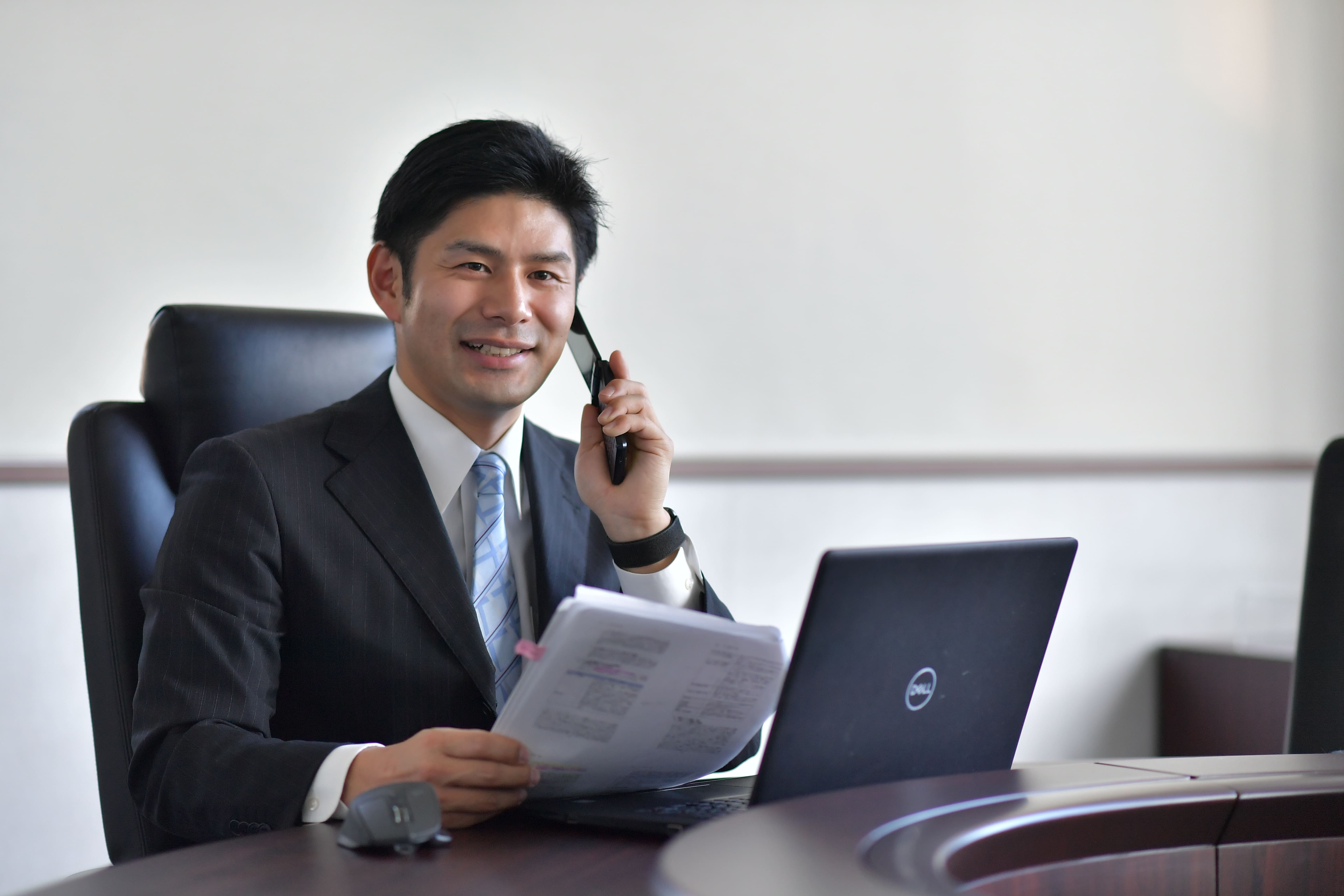 a person in a suit holding a phone and looking at a laptop