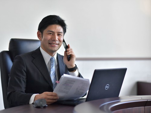 a person in a suit holding a phone and looking at a laptop