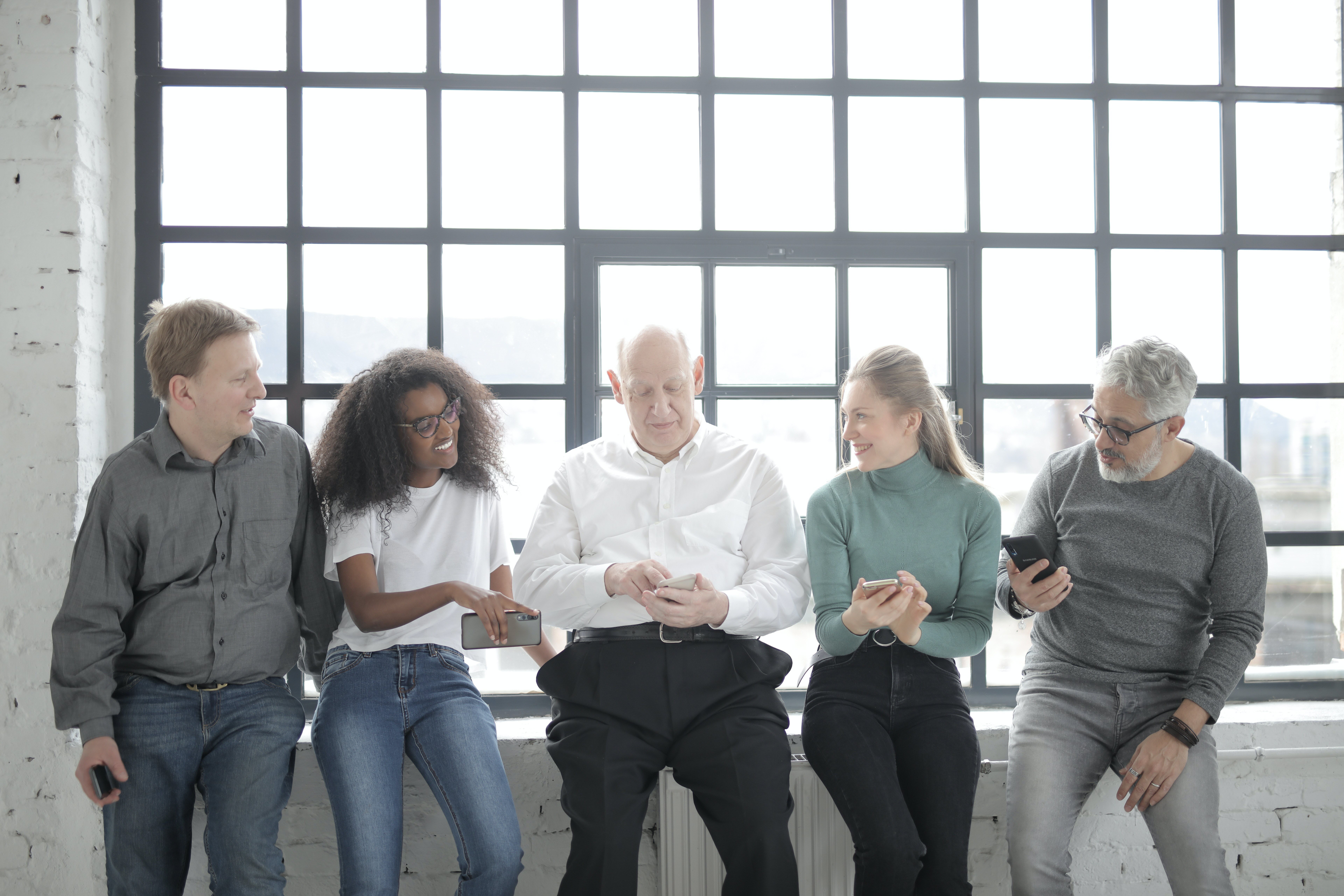 A Group Of People Sitting Beside A Steel Framed Window While 3863768