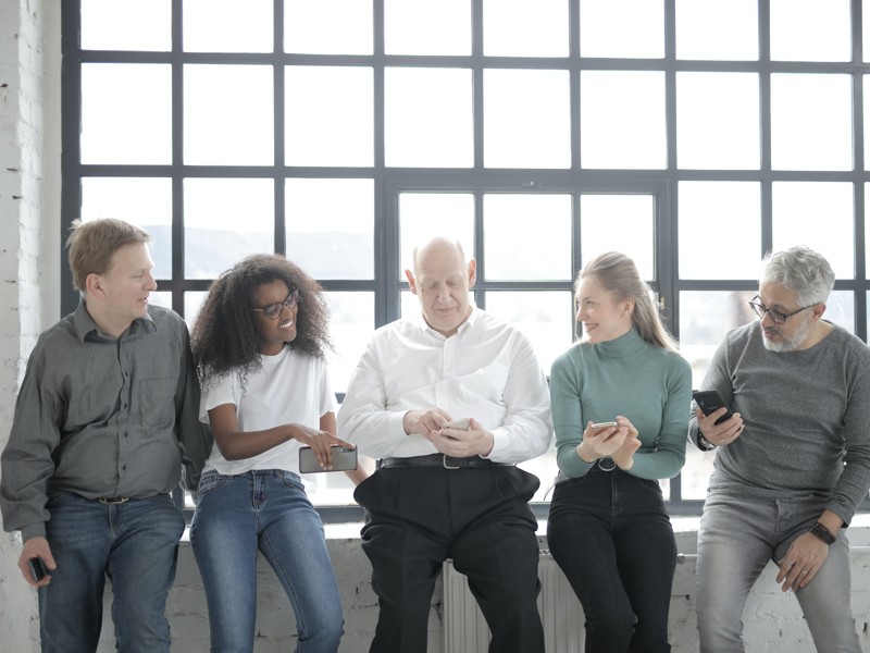 A Group Of People Sitting Beside A Steel Framed Window While 3863768