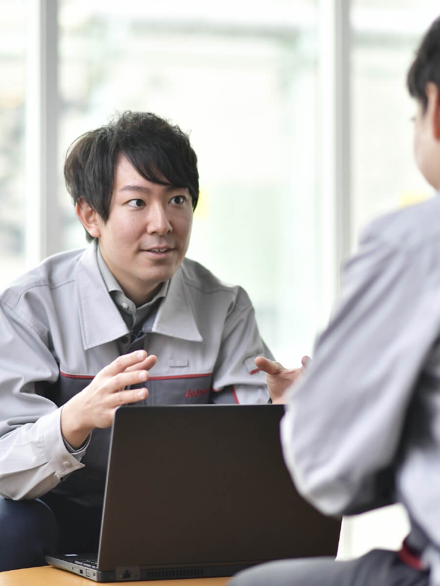 灰色のオーバーオールを着た人が他の人と話している