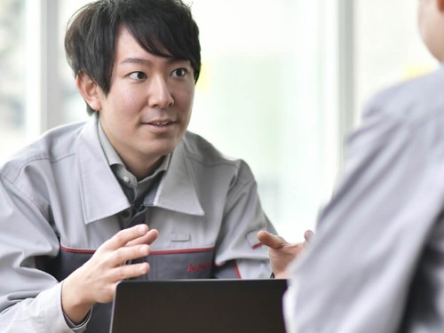 灰色のオーバーオールを着た人が他の人と話している