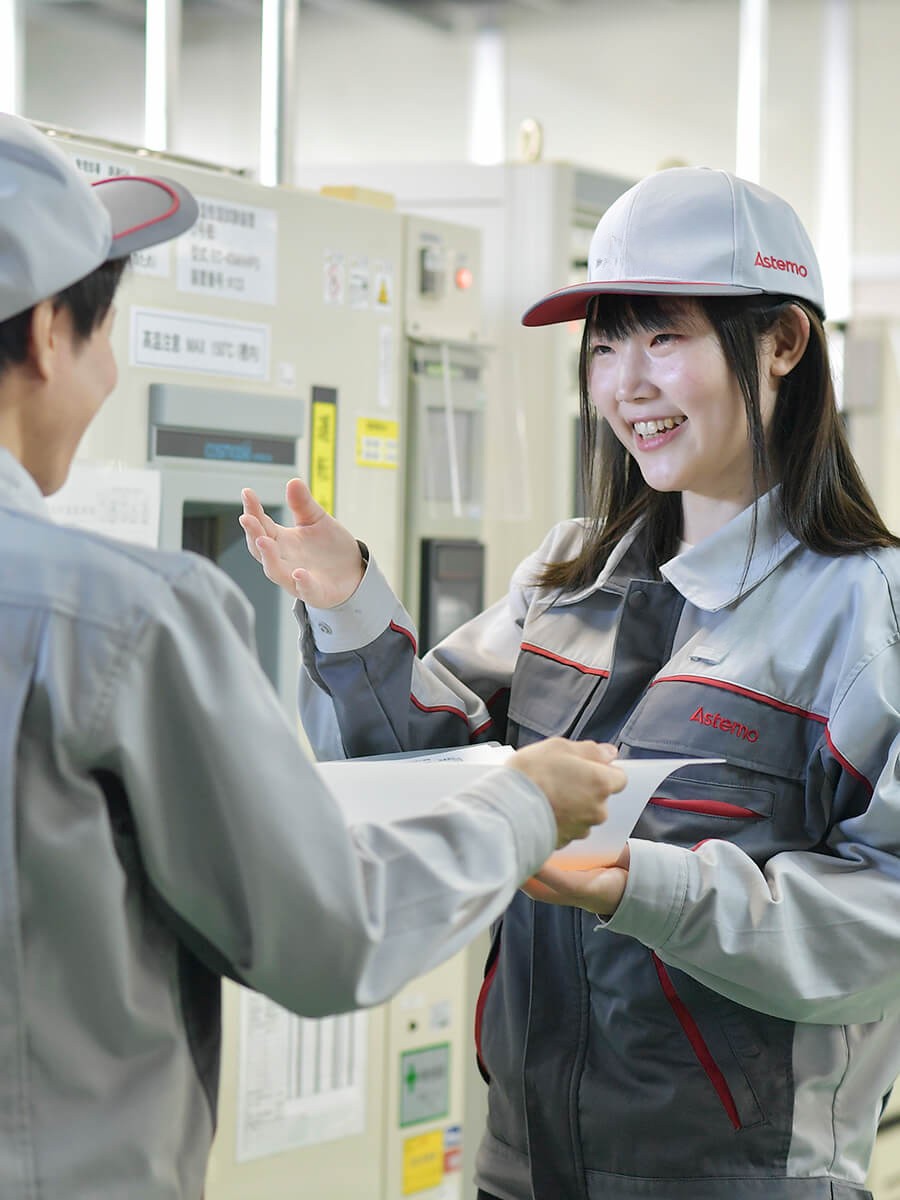 灰色の制服と帽子をかぶった人が機械に乗っている人と話している