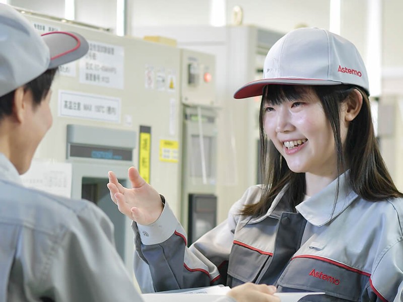 灰色の制服と帽子をかぶった人が機械に乗っている人と話している