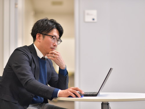 ノートパソコンを持ってテーブルに座っている人