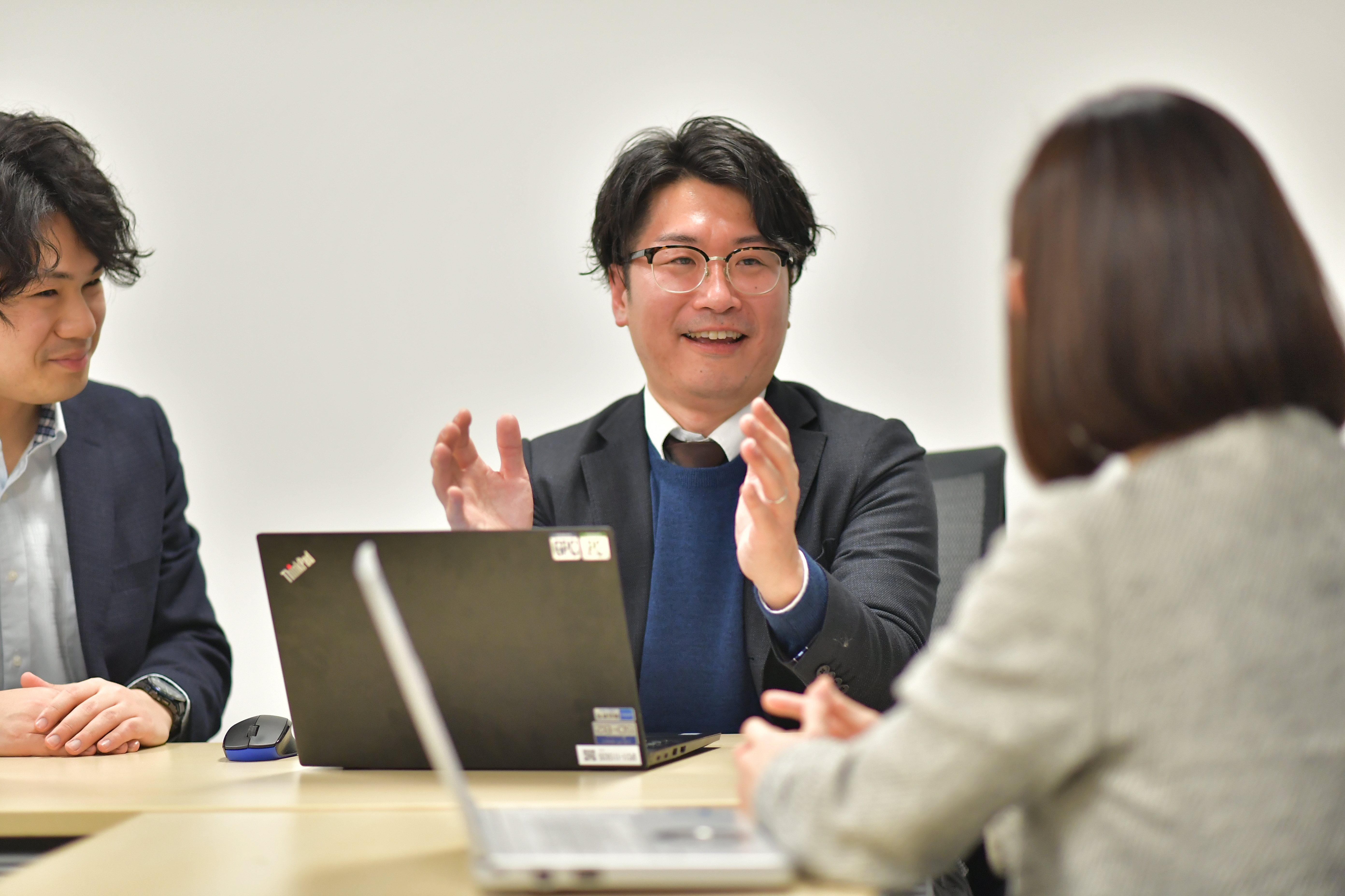 スーツとメガネを着た人が人と話している