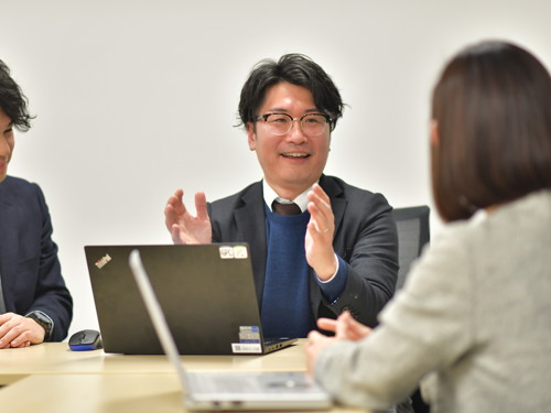 スーツとメガネを着た人が人と話している