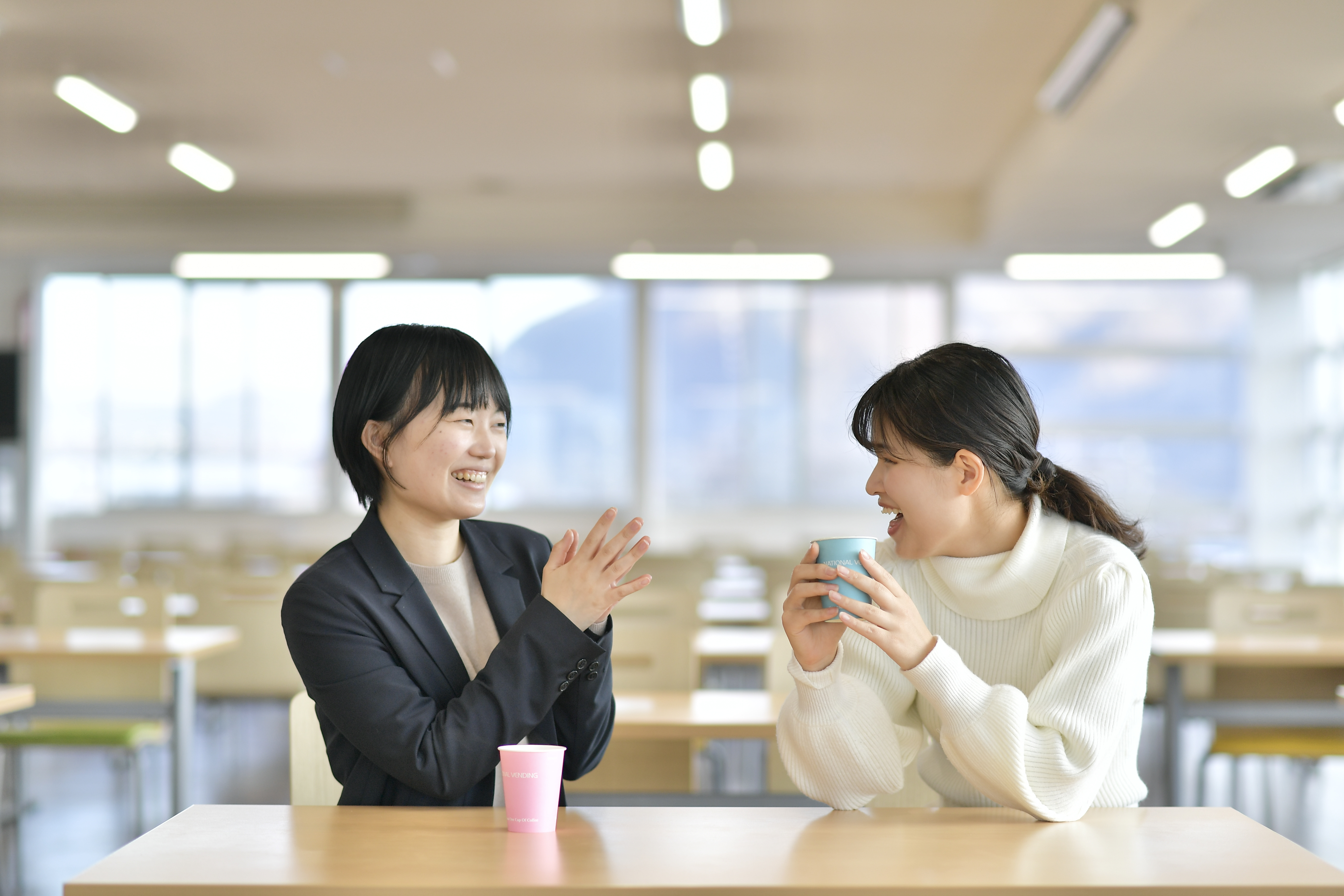 two women sitting at a table with cups