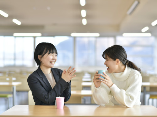 two women sitting at a table with cups