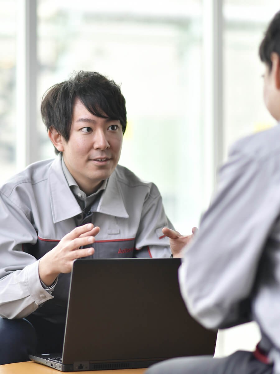 灰色のオーバーオールを着た人が他の人と話している