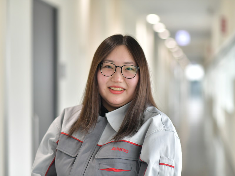 a person wearing glasses and a grey and white jacket